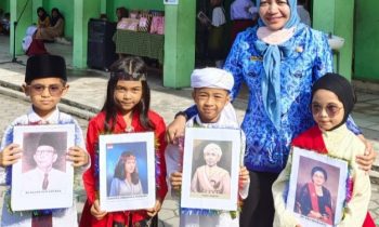 Siswa SDN 5 Baamang Hilir sambil membawa foto pahlawan yang wajahnya mereka tiru didampingi Kepsek Tuti Rahayu berpakaian warna biru