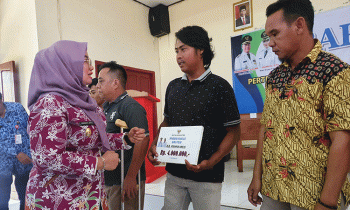 Irawati saat menyerahkan bantuan kepada masyarakat.