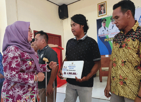 Irawati saat menyerahkan bantuan kepada masyarakat.