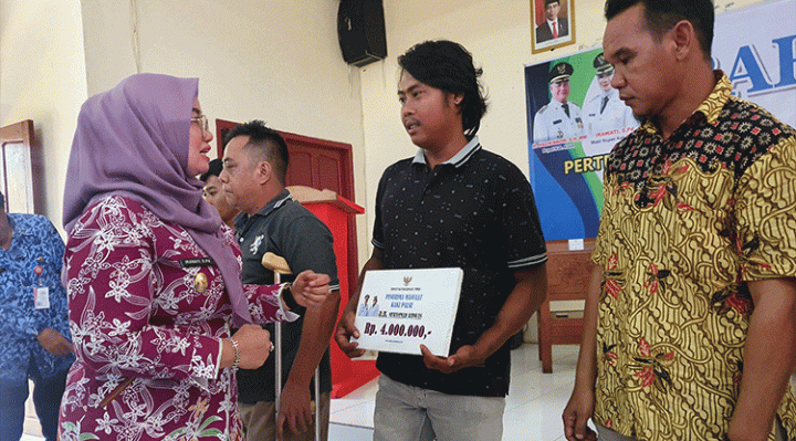 Irawati saat menyerahkan bantuan kepada masyarakat.