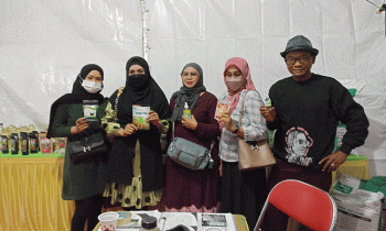 Mbah Surif paling kanan dan pengunjung stand Distan menunjukkan produk salah satunya Sari Bawang Dayak kreasi SDN 4 Ketapang Sabtu 12 November 2022.