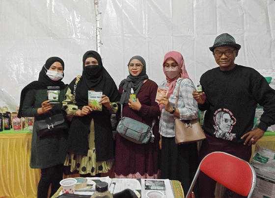 Mbah Surif paling kanan dan pengunjung stand Distan menunjukkan produk salah satunya Sari Bawang Dayak kreasi SDN 4 Ketapang Sabtu 12 November 2022.