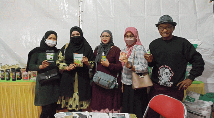 Mbah Surif paling kanan dan pengunjung stand Distan menunjukkan produk salah satunya Sari Bawang Dayak kreasi SDN 4 Ketapang Sabtu 12 November 2022.