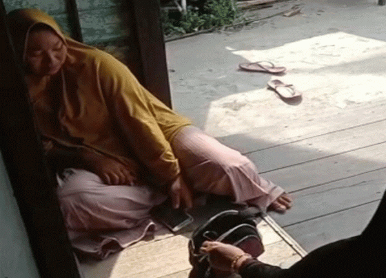 Seorang korban hipnotis kerudung kuning saat menangis di depan rumah warga.