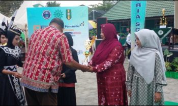 Guru Pembina Siswa SDN 4 Ketapang pada Ajang IPM Fest ke 2 Asykuriah menerima piala penghargaan juara 2 lomba baca puisi yang diraih siswanya