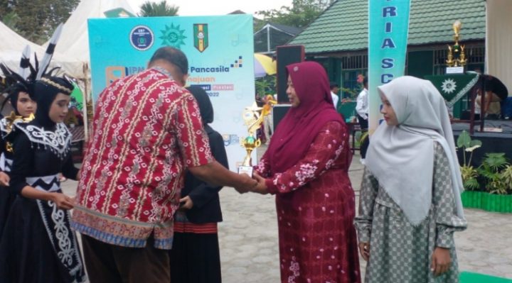 Guru Pembina Siswa SDN 4 Ketapang pada Ajang IPM Fest ke 2 Asykuriah menerima piala penghargaan juara 2 lomba baca puisi yang diraih siswanya