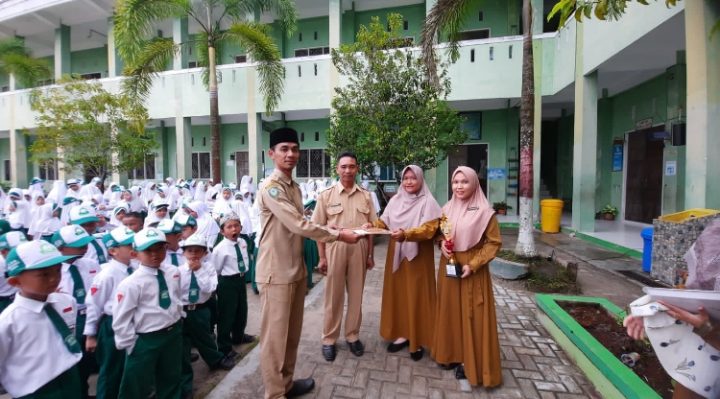 Perwakilan guru yang mengikuti Feserta Kreativitas Guru SD menyerahkan piala kepada Kepala SDIT Al Madaniyah untuk disimpan di sekolah tersebut