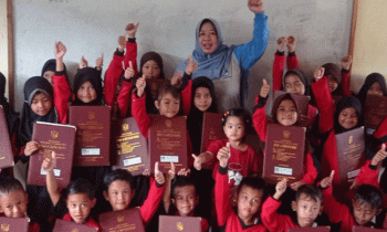 Seorang guru SDN 4 Ketapang Asykuriah berfoto bersama para siswanya sambil menunjukan rapor masing masing Jumat 23 Desember 2022.