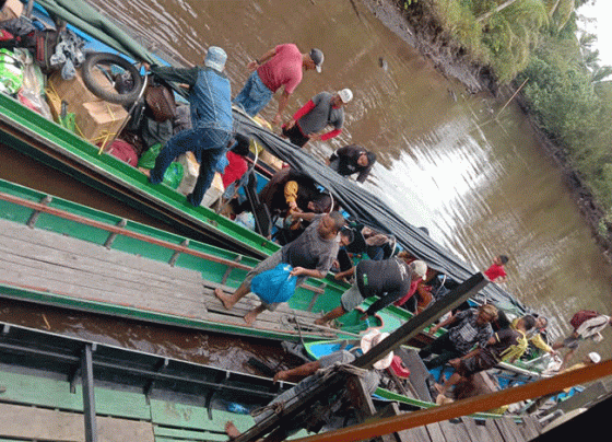 Penumpang saat proses berpindah kelotok dari kelotok besar ke kelotok kecil di Sungai Hantipan Kamis 5 Januari 2023.