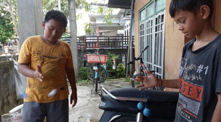 Rajit dan temannya bermain lato lato di depan rumah untuk mengisi waktu libur sekolah Kamis 5 Januari 2023
