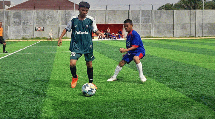 Dua siswa dari Tim Mini Soccer SMPN 2 Sampit kostum hijau vs SMPN 9 Sampit kostum biru berebut bola pada babak final di Jalan Nyai Enat Sampit Jumat 10 Februari 2023.