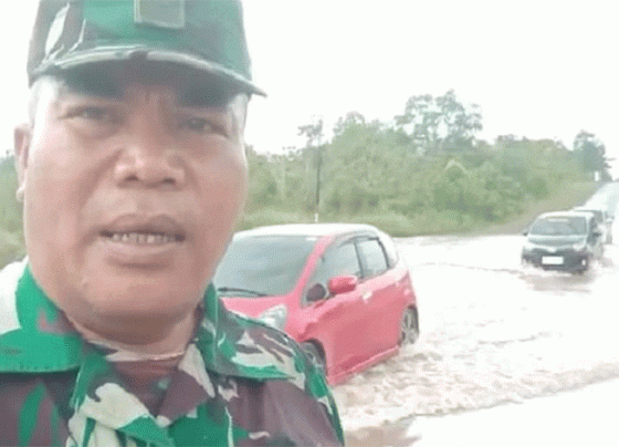 Seorang aparat TNI dari Kodim 1019 Katingan mengatur arus lalulintas di Jalan Trans Kakimantan Km 18 5 Kereng Pangi Sampit yang tergenang akibat hujan lebat Selasa 28 Februari 2023.
