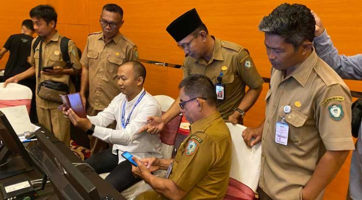 Kepala Disdukcapil Kotim Agus Tripurna Tangkasiang kopiah hitam saat membantu masyarakat memverifikasi aplikasi IKD
