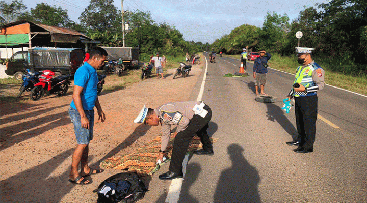 Polisi menutup mayat korban meninggal dengan kain jarik di lokasi kecelakaan di Jalan Jendaral Sudirman Km 26.