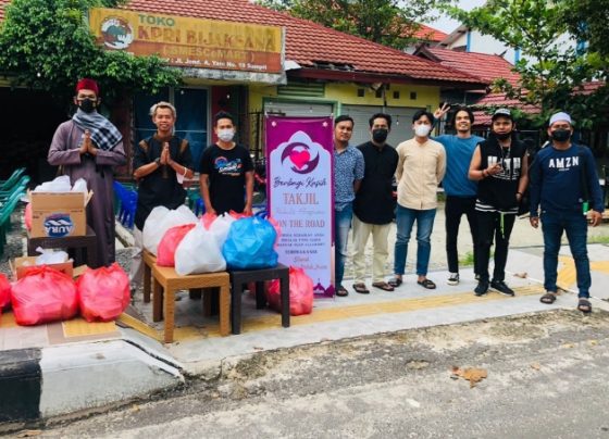 Para pemuda berbagi kasih saat berfoto bersama sebelum membagikan takjil di tepi jalan