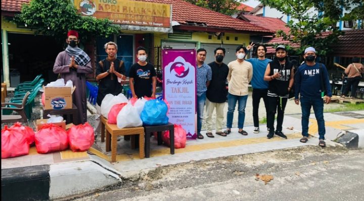 Para pemuda berbagi kasih saat berfoto bersama sebelum membagikan takjil di tepi jalan