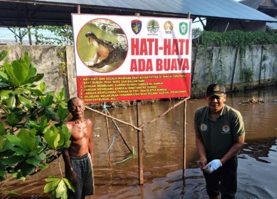 Komandan BKSDA Pos Jaga Sampit Muriansyah bersama warga usai memasang ppan peringatan keberadaan buaya di Sungai Mentawa, Rabu, 31 Mei 2023.