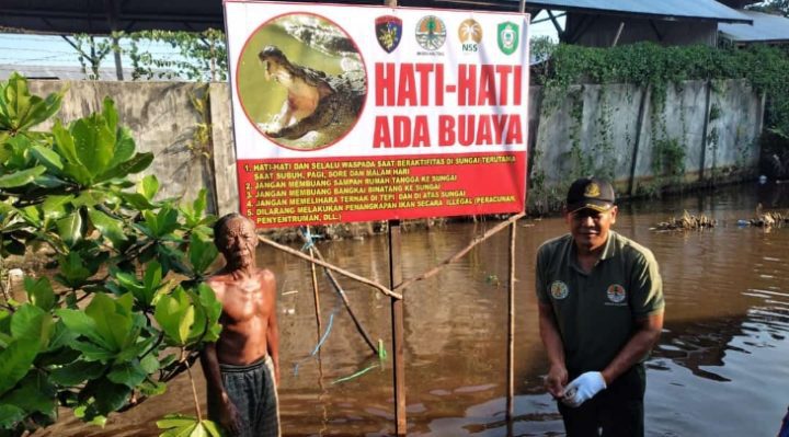 Komandan BKSDA Pos Jaga Sampit Muriansyah bersama warga usai memasang ppan peringatan keberadaan buaya di Sungai Mentawa, Rabu, 31 Mei 2023.