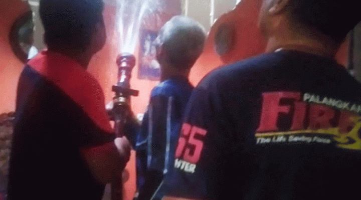 Petugas pemadam kebakaran berupaya memadamkan api yang berada di flapon rumah warga.