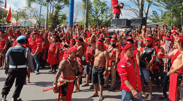 Seorang polisi terlihat berjaga di tengah kerumunan pasukan merah atau TBBR yang menggelar aksi damai di depan Kantor Bupati Kotim, Kamis, 8 Juni 2023.