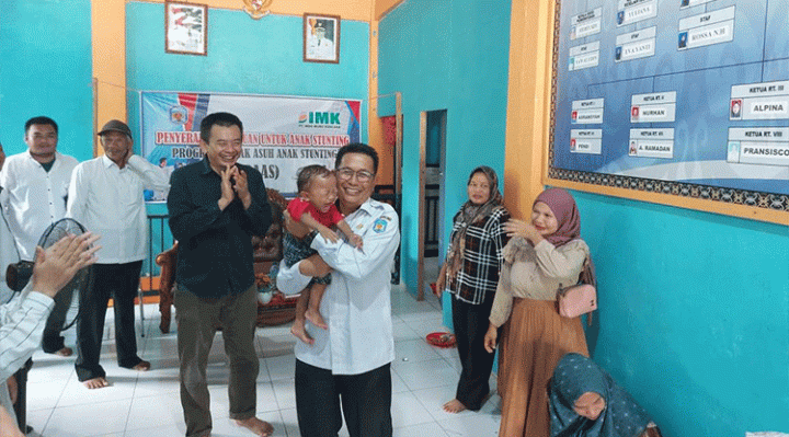 Wakil Bupati Mura Rejikinoor, S.Sos didamping Manajer CSR PT IMK Budhi Bakti saat menggendong bayi di aula Desa Mangkahui, Rabu, 12 Juli 2023.