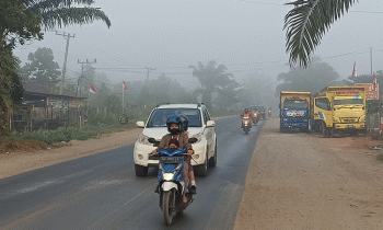 Pengendara motor membonceng anaknya di Jalan Jenderal Sudirman Km 3, Sampit pukul 06.00 WIB menerobos asap karhutla tebal, Rabu, 16 Agustus 2023.