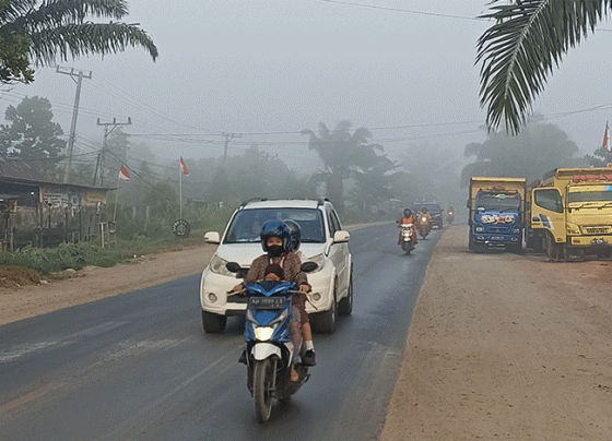 Pengendara motor membonceng anaknya di Jalan Jenderal Sudirman Km 3, Sampit pukul 06.00 WIB menerobos asap karhutla tebal, Rabu, 16 Agustus 2023.