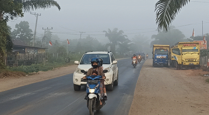 Pengendara motor membonceng anaknya di Jalan Jenderal Sudirman Km 3, Sampit pukul 06.00 WIB menerobos asap karhutla tebal, Rabu, 16 Agustus 2023.