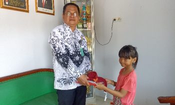 Kepala SDN 1 Baamang Tengah, Hasanuddin MS kiri memberikan bantuan kepada siswi korban kebakaran kanan di Jalan Muchran Ali, Sabtu 30 September 2023m