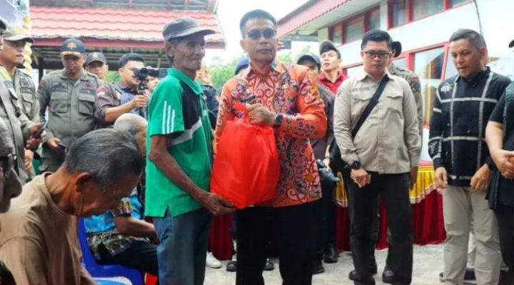 Pj Bupati Murung Raya Hermon, saat menyerahkan sembako murah kepada salah seorang warga.