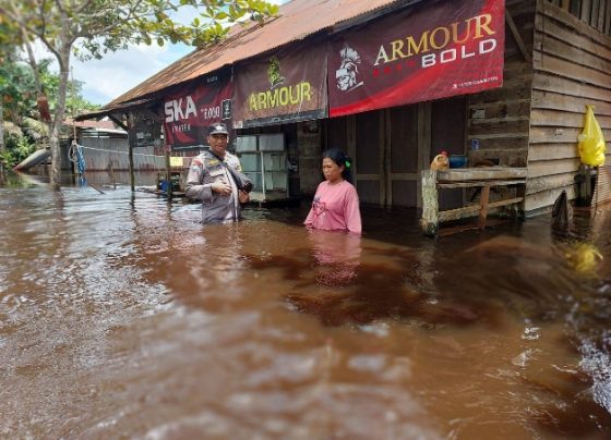 Seorang anggota Polri saat berbincang dengan warga di Desa Sei Ubar Mandiri, yang rumahnya terendam banjir, Minggu, 18 Februari 2023.