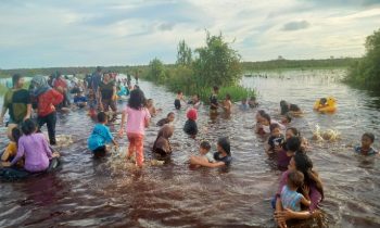 Liburan gratis, warga berenang saat banjir menggenangi jalan di Kereng Bengkirai.
