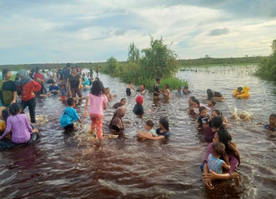 Liburan gratis, warga berenang saat banjir menggenangi jalan di Kereng Bengkirai.