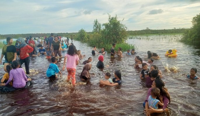 Liburan gratis, warga berenang saat banjir menggenangi jalan di Kereng Bengkirai.