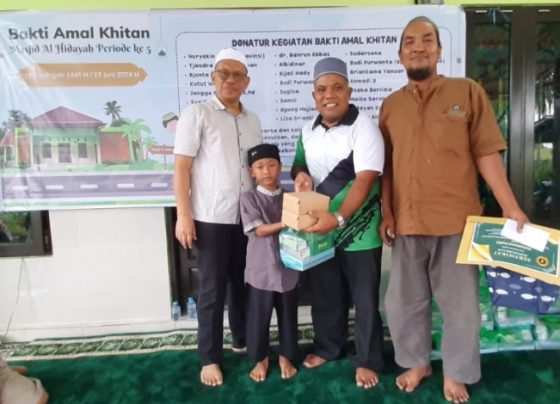 Pj Sekda Seruyan dr Bahrun Abbas bersama ketua panitia kegiatan saat menyerahkan bingkisan kepada salah seorang anak peserta khitan