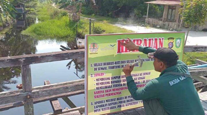 Komandan BKSDA Resor Sampit Muriansyah memasang spanduk imbauan waspada buaya.