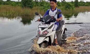 Seorang warga melintasi genangan air yang merendam wilayah Ketimpun, Kota Palangka Raya