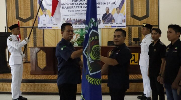 Ketua PWI Kalteng Jainal memberikan bendera PWI kepada Ketua PWI Katingan Ancu pada konferensi di Aula Dinas PUPR, Kamis, 19 Juni 2025
